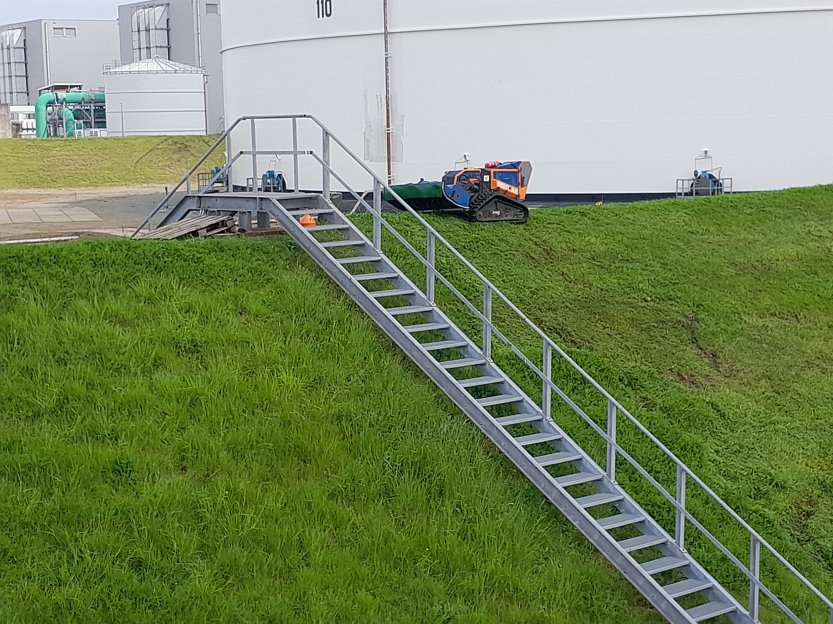Radiografische rupsmaaier van Van der Hoef Groen & Techniek aan het werk op industrieel talud